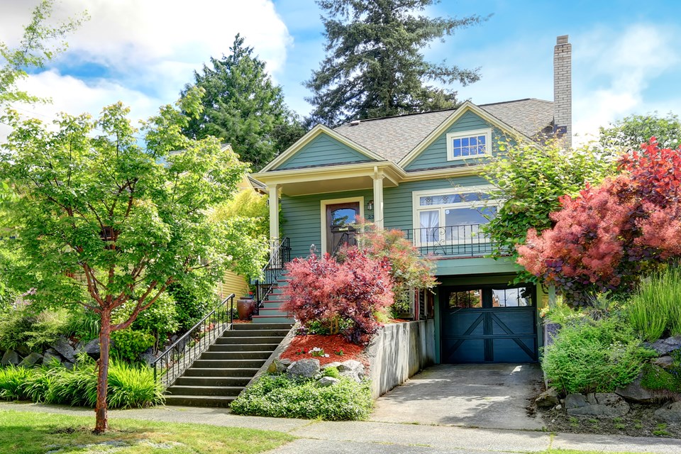 front of house features beautiful flowers and garage.